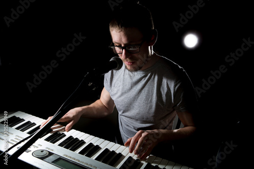 keyboarder is playing and singing on dark background