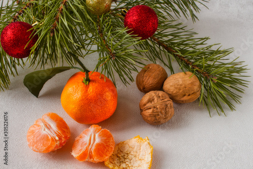 Christmas composition of fruits and nuts. two juicy halves of tangerine and walnuts lie under the Christmas tree.