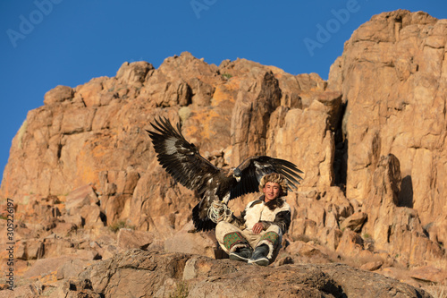 Portrait of a young kazakh eagle hunter with his majestic golden eagle in the steppe. Ulgii, Mongolia. photo