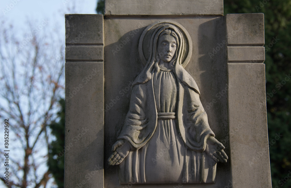 Fototapeta premium Monument and candles in the cemetery. All Saints Day in Poland. Stone sculpture.
