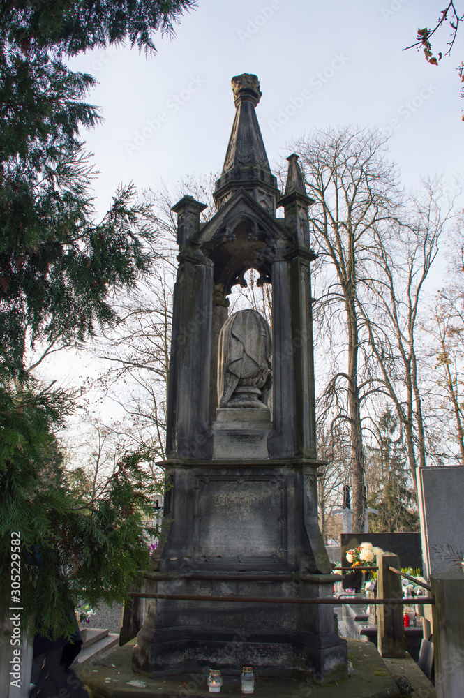 Fototapeta premium Monument and candles in the cemetery. All Saints Day in Poland. Stone crypt in the cemetery.