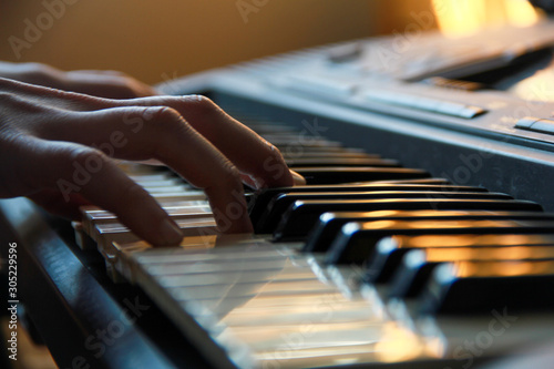 Details of a hand playing on keyboard under a smooth light