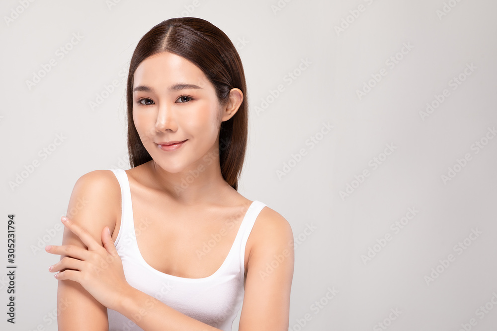 Beautiful Young Asian Woman Looking While Touching Shoulder feeling so happy and cheerful with healthy Clean and Fresh skin,isolated on gray background,Beauty Cosmetology Concept Beautiful Young Asian Woman Looking While Touching Shoulder feeling so happy and cheerful with healthy Clean and Fresh skin,isolated on gray background,Beauty Cosmetology Concept