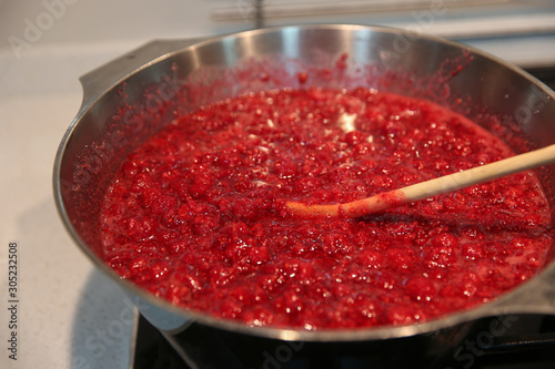 Cooking raspberry jam in a bowl. Top view.