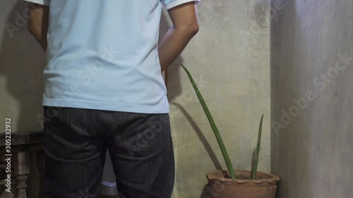 A man peeing by using urinal in men public toilet
