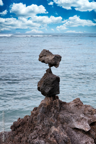 Native rocks stacked vertically with ocean and blue sky