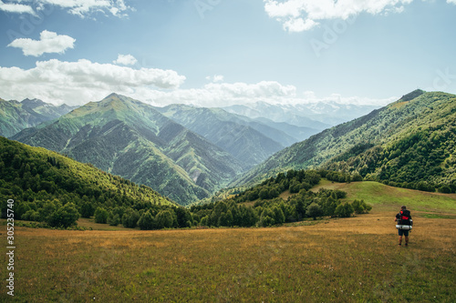 Backpacker stands and looks on mountains and valley. Photo from trek in Svaneti region, Georgia - Mestia to Ushguli