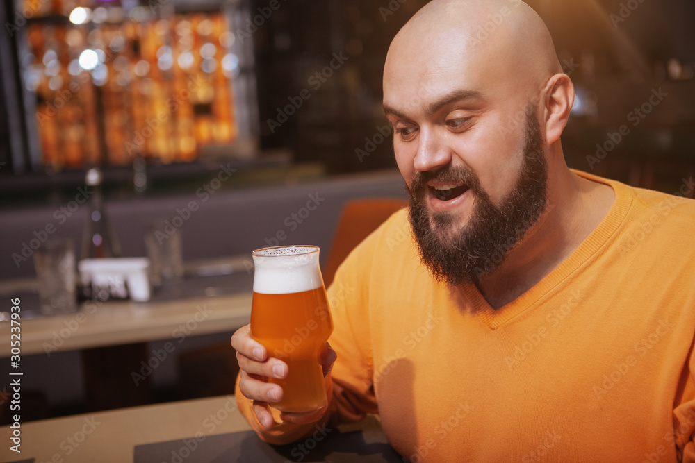 Excited man looking at his beer glass, copy space. Brewery, craft beer concept Excited man looking at his beer glass, copy space. Brewery, craft beer concept