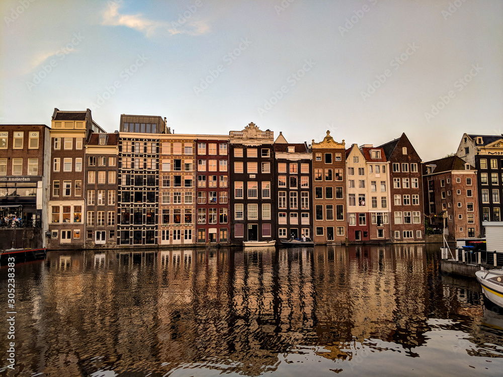 Traditional old buildings reflected on the canal's waters in Amsterdam, the Netherlands