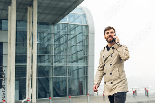Businessman on the airport holding mobile phone. © Petryshak