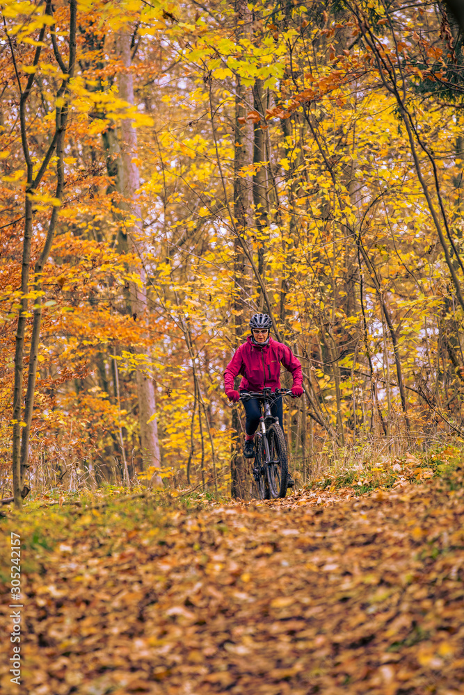 nice senior woman riding her mountainbike on the autumnal forest trails near Stuttgart, beautiful warm colors nice senior woman riding her mountainbike on the autumnal forest trails near Stuttgart, beautiful warm colors