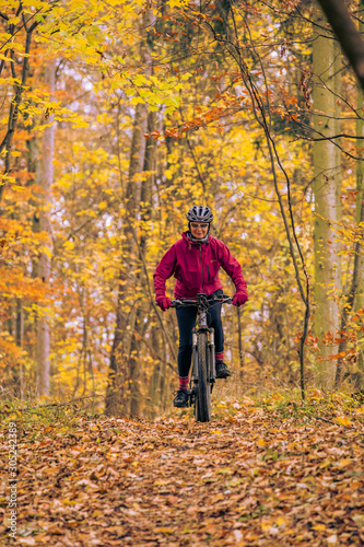 nice senior woman riding her mountainbike on the autumnal forest trails near Stuttgart  beautiful warm colors