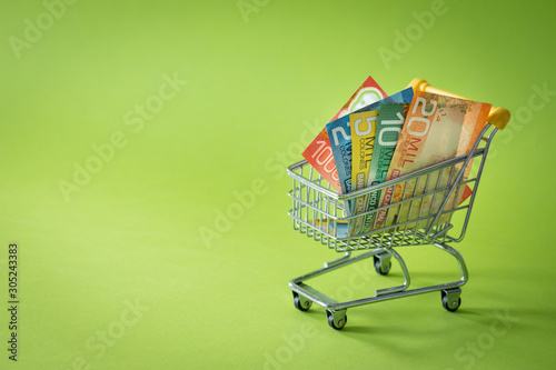 Miniature shopping trolley with Costa rican money. The concept of shopping and the power of the economy. Place for text