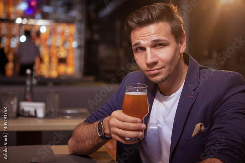 Attractive elegant man smiling to the camera, enjoying tasty beer at the p