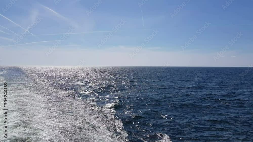 Powerful waves following the ship. Waves behind the stern of the ship. Track from the engines of the ship. Cruise liner sails on the blue ocean. The waves from the ship go to the horizon. Powerful waves following the ship. Waves behind the stern of the ship. Track from the engines of the ship. Cruise liner sails on the blue ocean. The waves from the ship go to the horizon.