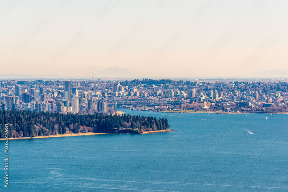 View over Cityscape on sunny day with ocean and trees.