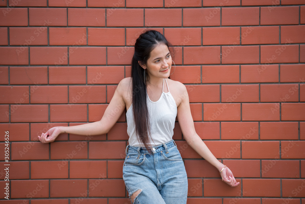 Portrait of beautiful asian chic girl pose for take a picture on brick wall background,Lifestyle of teen thailand people,Modern woman happy concept,Punk rock style