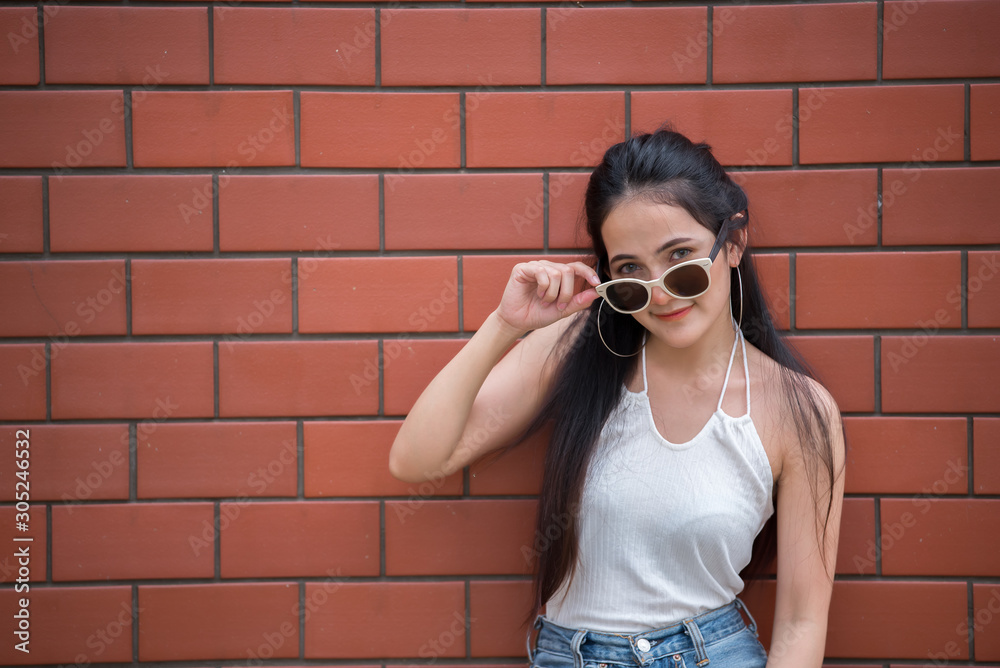 Portrait of beautiful asian chic girl pose for take a picture on brick wall background,Lifestyle of teen thailand people,Modern woman happy concept,Punk rock style Portrait of beautiful asian chic girl pose for take a picture on brick wall background,Lifestyle of teen thailand people,Modern woman happy concept,Punk rock style