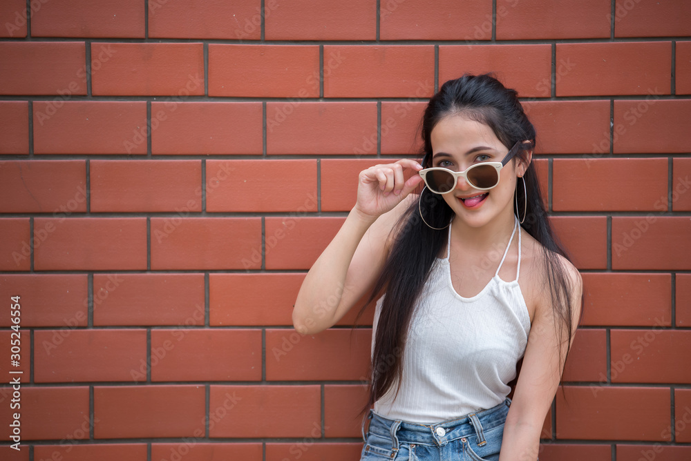 Portrait of beautiful asian chic girl pose for take a picture on brick wall background,Lifestyle of teen thailand people,Modern woman happy concept,Punk rock style Portrait of beautiful asian chic girl pose for take a picture on brick wall background,Lifestyle of teen thailand people,Modern woman happy concept,Punk rock style