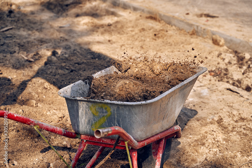 they throw earth into a wheelbarrow.