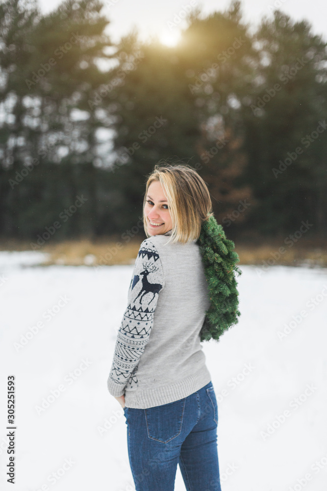 Stylish Christmas wreath in the hands of a girl on a winter forest background. Back view of the woman, looking at camera and smiling, holding New Year wreath Stylish Christmas wreath in the hands of a girl on a winter forest background. Back view of the woman, looking at camera and smiling, holding New Year wreath