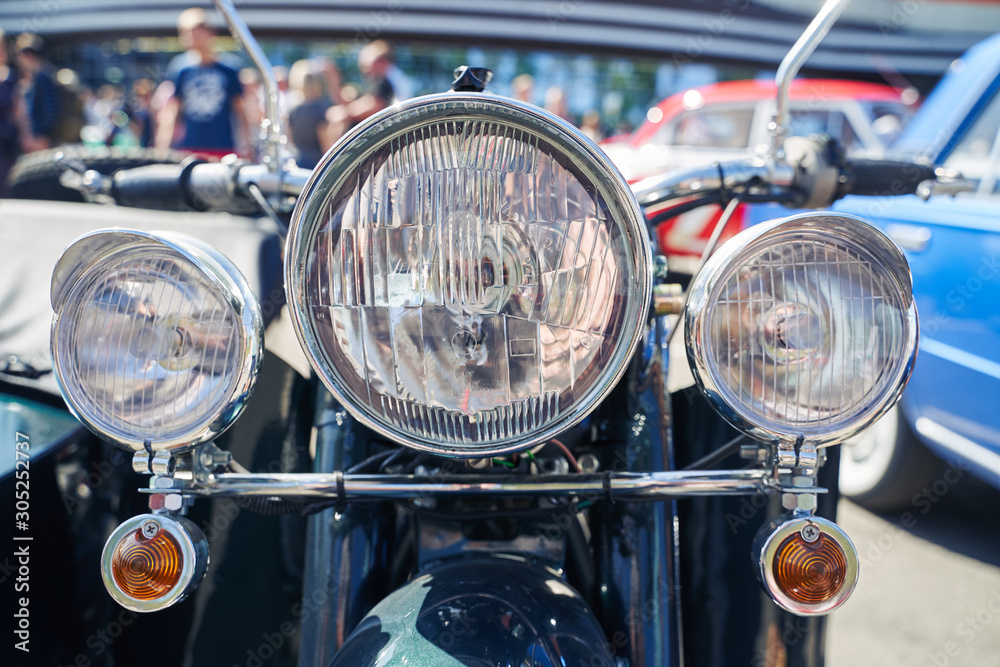 Closeup of the headlight of a retro motorcycle at an auto show.