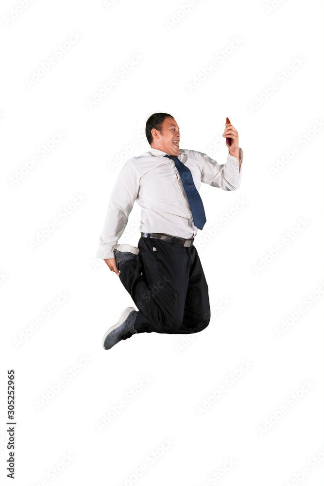 Happy businessman jumping while looking at his mobile phone isolated over white