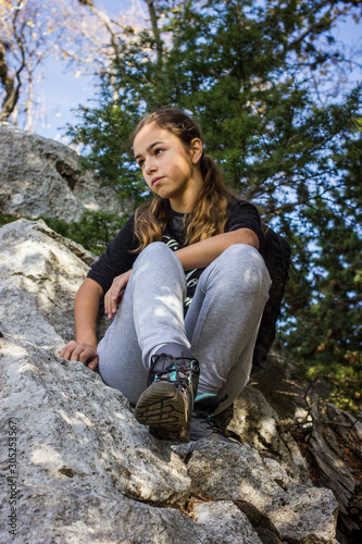 Foto Young beautiful teenager girl sitting on a rock in a forest