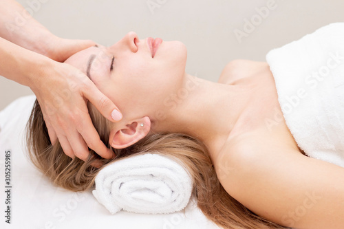 Young woman enjoying massage in spa salon. Face massage. Closeup of young woman getting spa massage treatment at beauty spa salon.Spa skin and body care. Facial beauty treatment.Cosmetology.