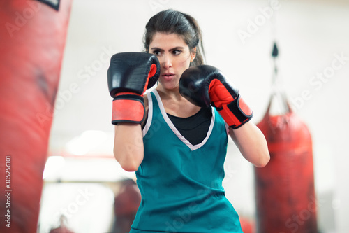 A young female boxer punching a bag in the gym