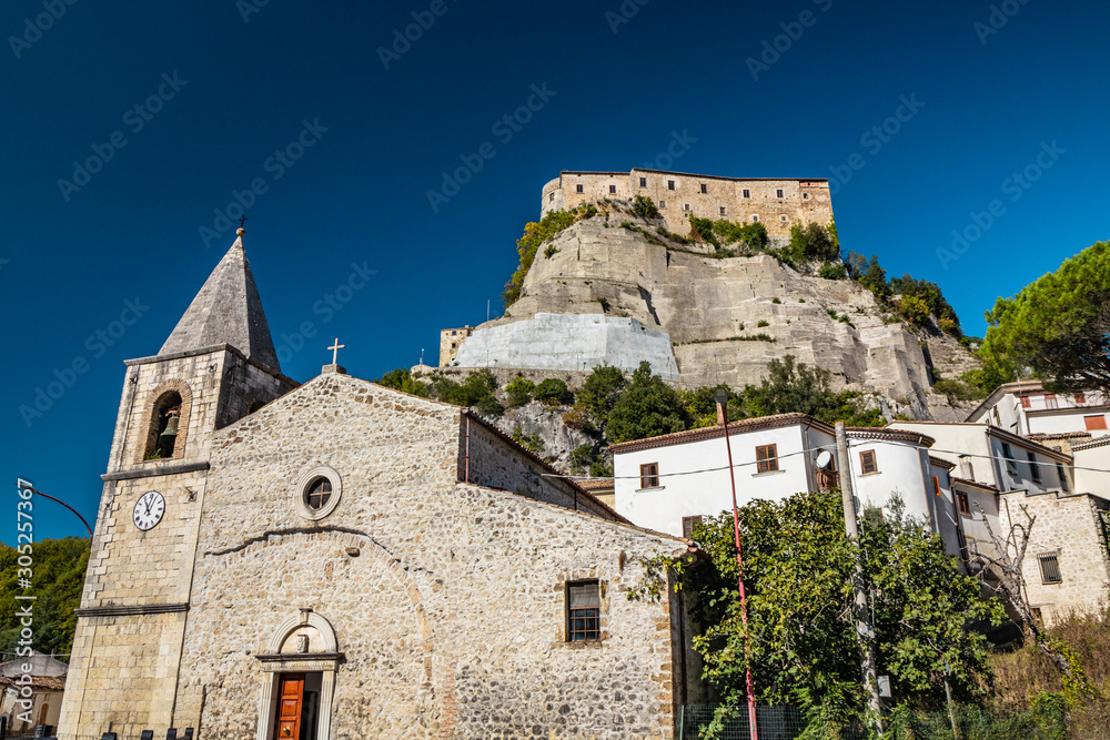 A view of the ancient village of Cerro al Volturno. The Pandone castle stands on top of the hill, on a rock spur. The town church with the bell tower and the clock. Isernia, Molise, Italy.