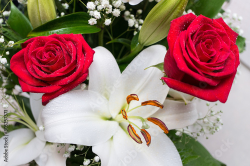 Bouquet of flowers close-up on a white background. Two red roses and a white lily.