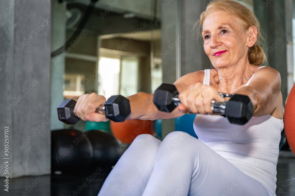 Senior woman Caucasian training arm with dumbell at fitness gym. Senior woman Caucasian training arm with dumbell at fitness gym.