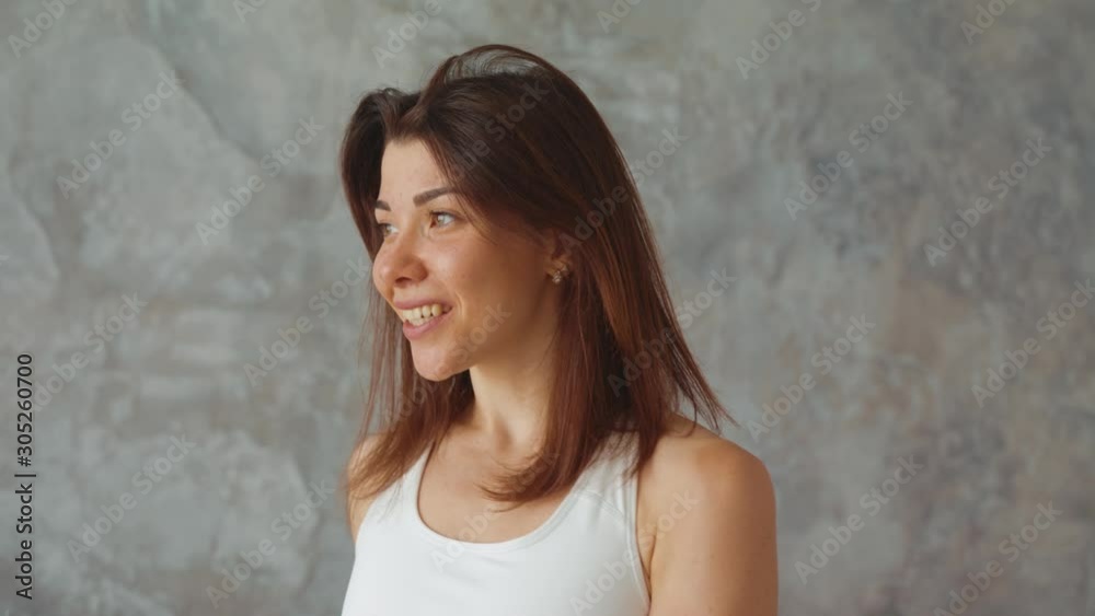 Slim girl in white top smiles and fixes her hair Slim girl in white top smiles and fixes her hair