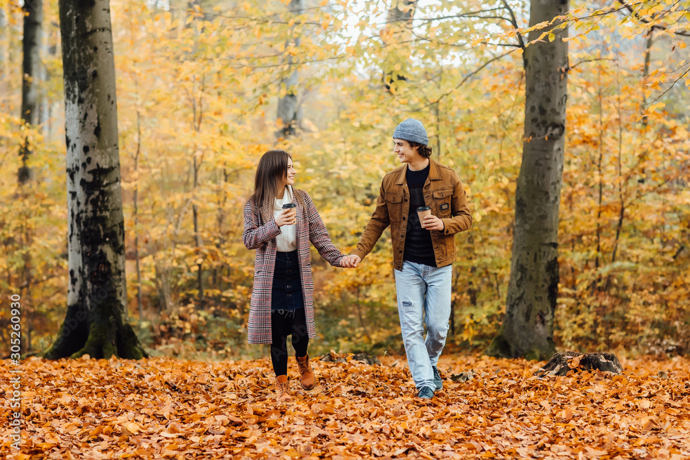 Family and hot autumn drink concept. Couple in love holding cups of tea or coffee and walking. Love story. Family and hot autumn drink concept. Couple in love holding cups of tea or coffee and walking. Love story.