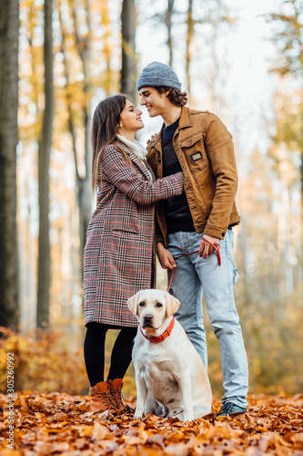 Owners walking their labrador retriever outdoors on autumn day. © Тарас Нагирняк