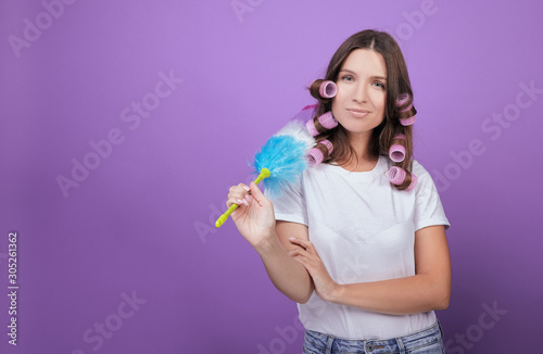 Girl in a white T-shirt and pink curlers does the cleaning.