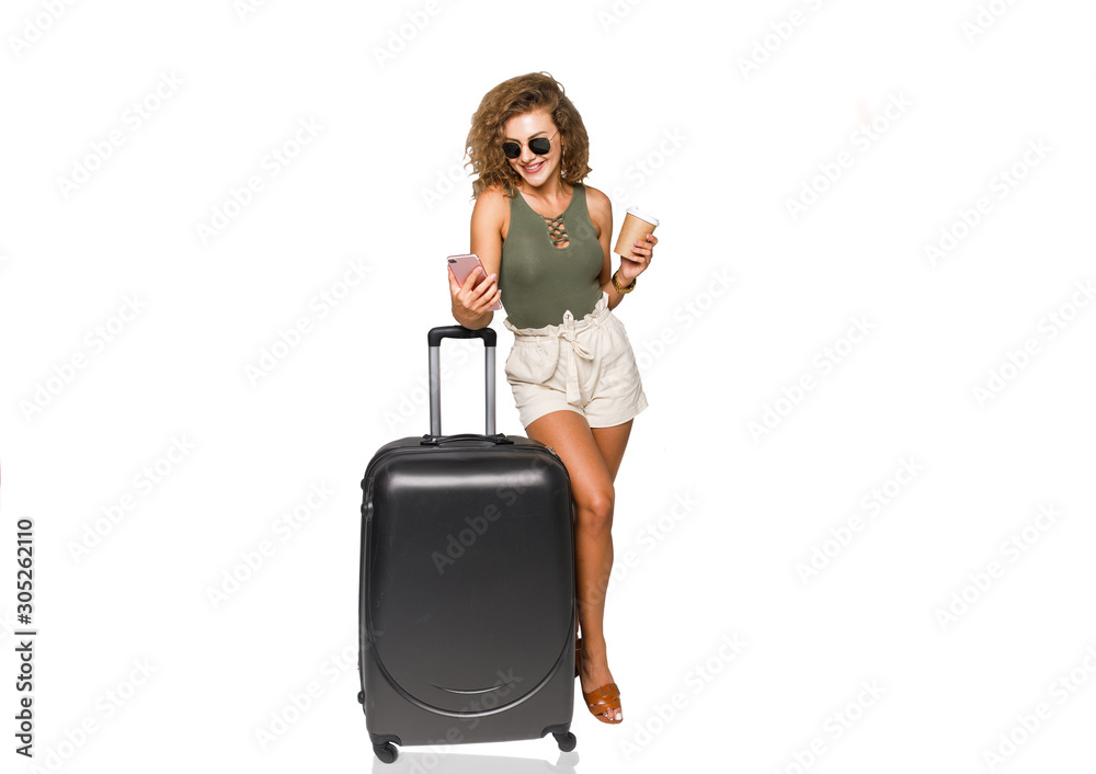 Photo of young happy woman, tourist in casual clothing ready for weekend with cup of coffee and phone, big suitcase. Photo of young happy woman, tourist in casual clothing ready for weekend with cup of coffee and phone, big suitcase.