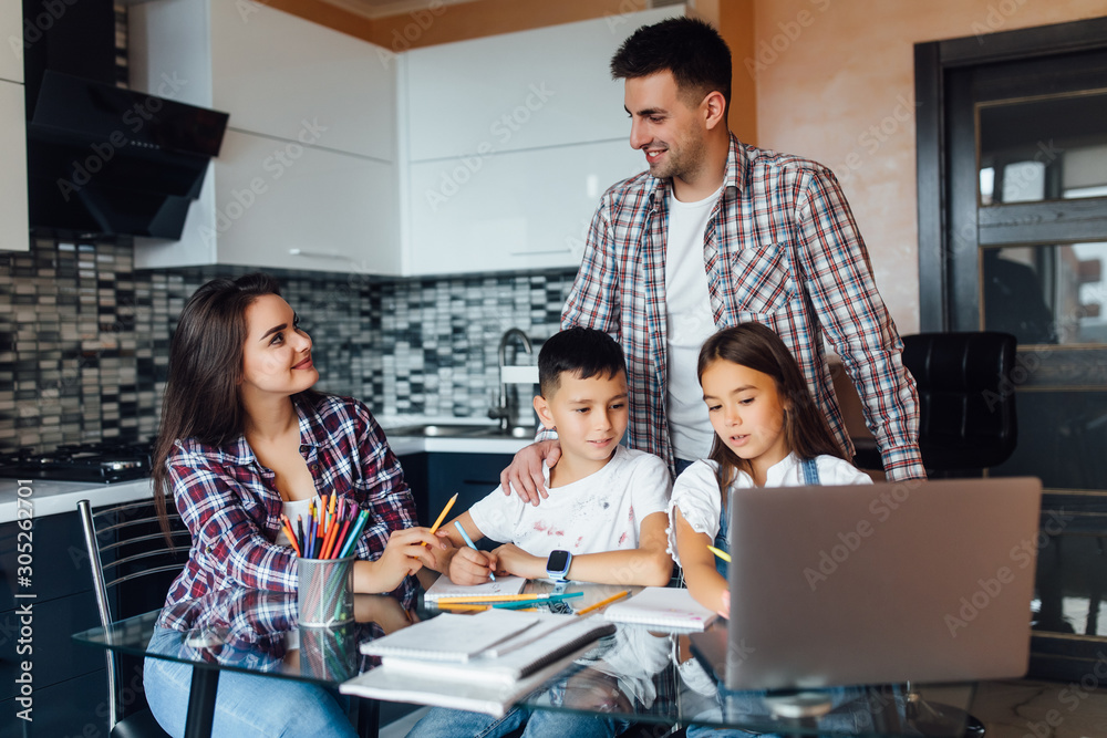 Happy familly, brunette mother with father and their adorable children doing homework for school.