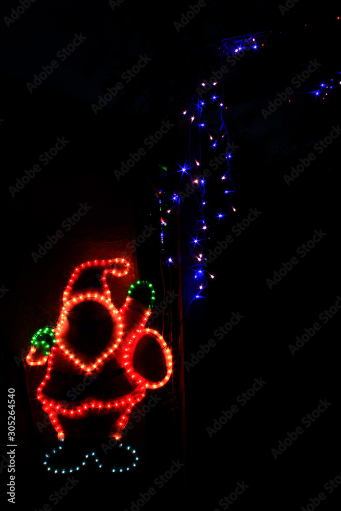 Christmas decoration for outdoors or indoors with multicolored lights.  Bright Santa Claus with a sheaf of blue LED stars.