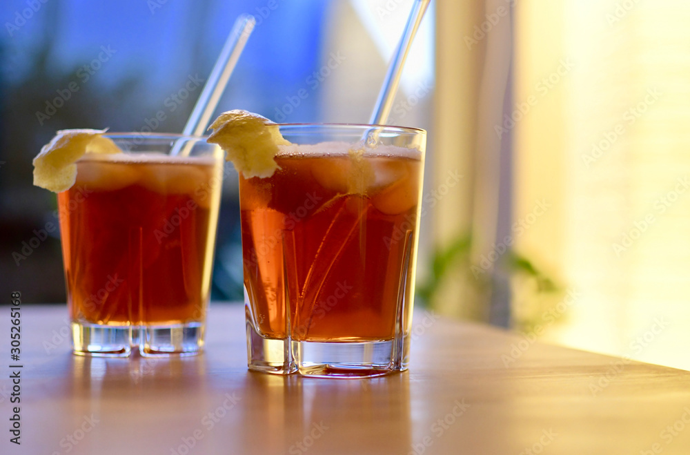 two glasses fresh horse neck cocktail on a wooden table orange brown color with lemon peel and drinking straw blurred background space for text two glasses fresh horse neck cocktail on a wooden table orange brown color with lemon peel and drinking straw blurred background space for text