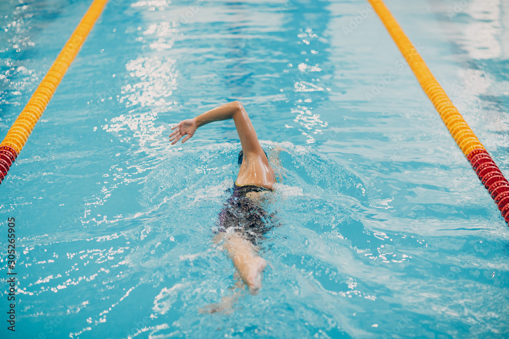 Young woman swimmer swims in swimming pool
