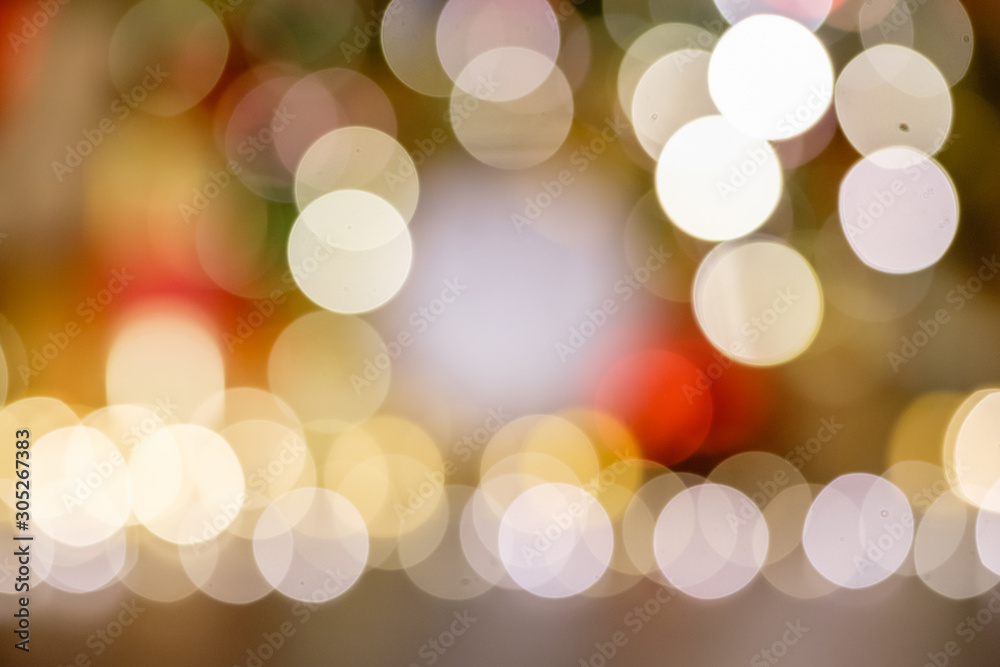 Fototapeta premium Blurry bokeh warm white light lights shining near the blurry Christmas decor and New Year tree. Background concept for Happy New Year greetings and advertising. Place for text