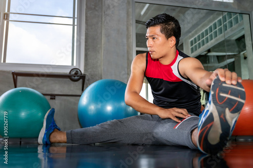 Young Asian attractive man stretching at fitness gym. © Suthiporn