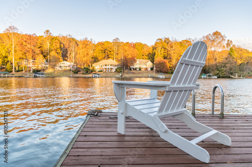 Adirondack style chairs on a dock, overlooking a beautiful, quiet, lake. Concept of a relaxing vacation in a remote area.
