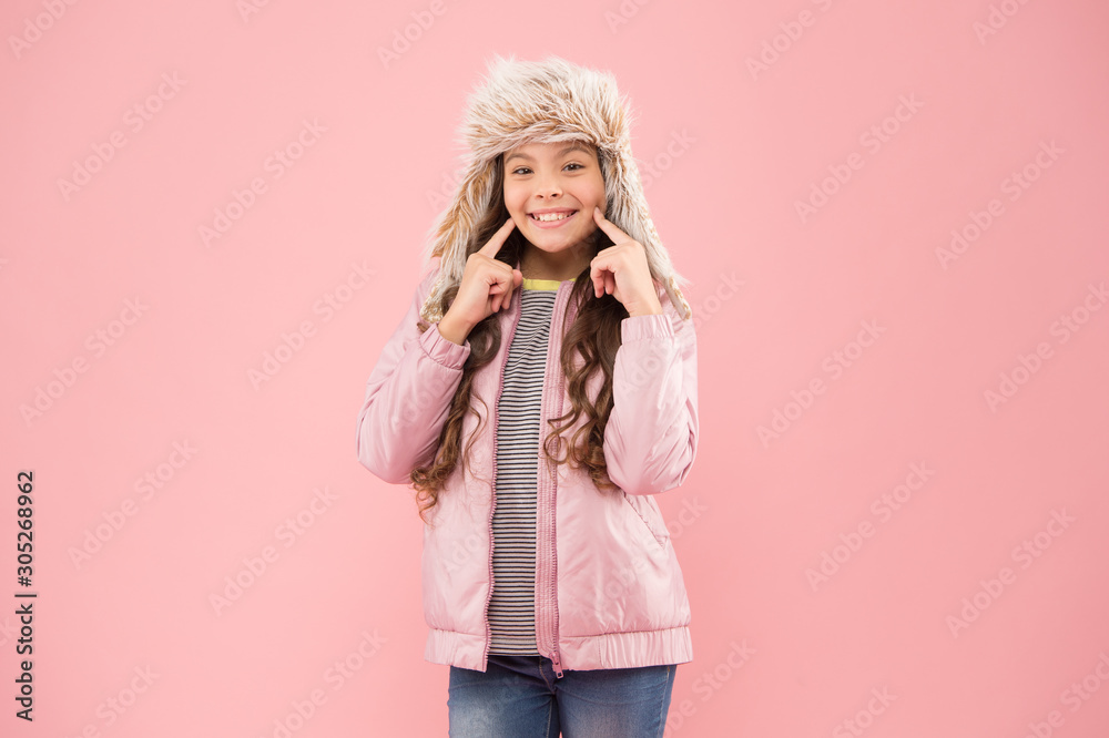 Wide sincere smile. Warm hat for cold weather. Faux fur trend. Girl long curly hair wear fur hat with ear flaps pink background. Soft furry accessory. Child long hair soft fur hat enjoy softness Wide sincere smile. Warm hat for cold weather. Faux fur trend. Girl long curly hair wear fur hat with ear flaps pink background. Soft furry accessory. Child long hair soft fur hat enjoy softness