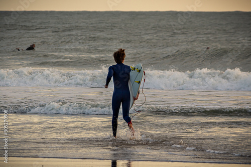 A surfer entering in the sea, Caravelos beach, Portugal
