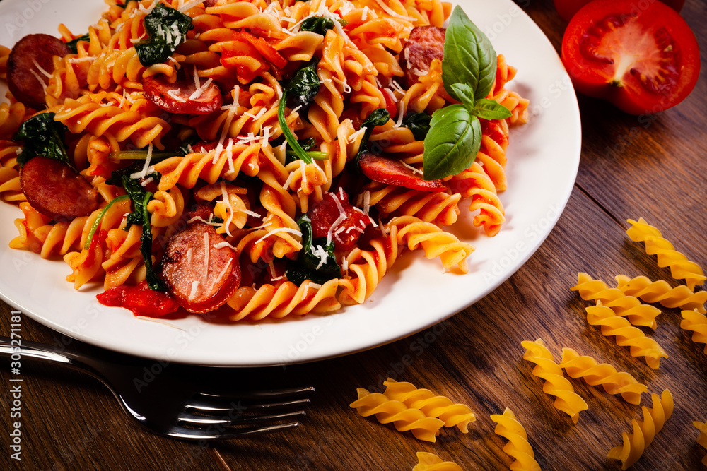 Fusilli with sausages and vegetables on wooden table Fusilli with sausages and vegetables on wooden table