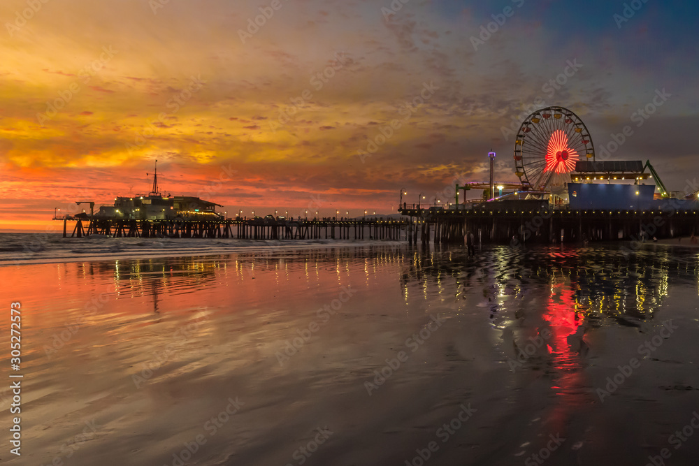 Santa Monica Pier at Sunset. Heart light on ferris wheel with sky and pier reflection in water.