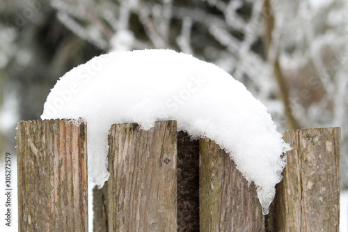 old wooden fence covered with a white snowdrift on a winter background, seasonal, weather, first snowfall concept, horizontal, close-up